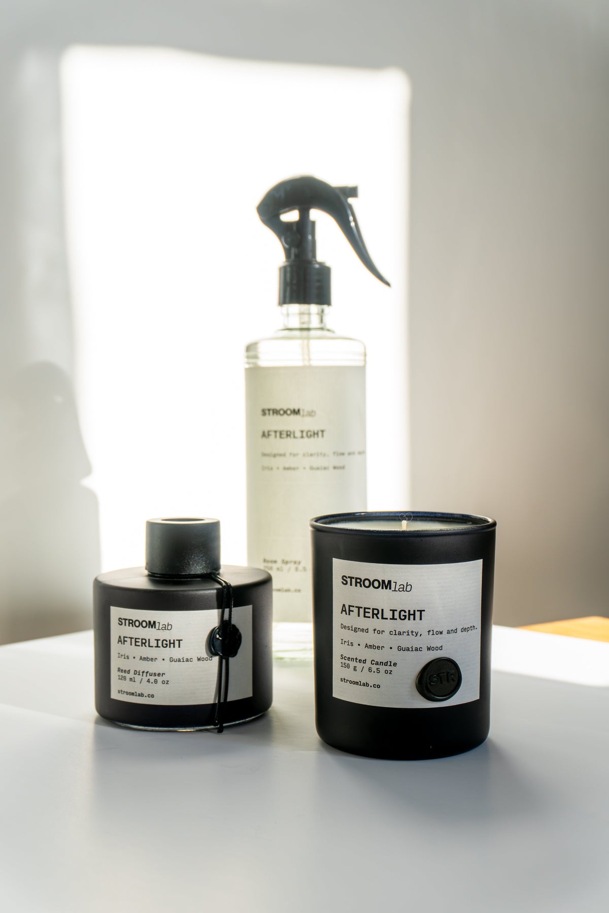 Gün ışığında STROOMlab Afterlight mum, oda spreyi ve çubuklu oda kokusu şişesi.